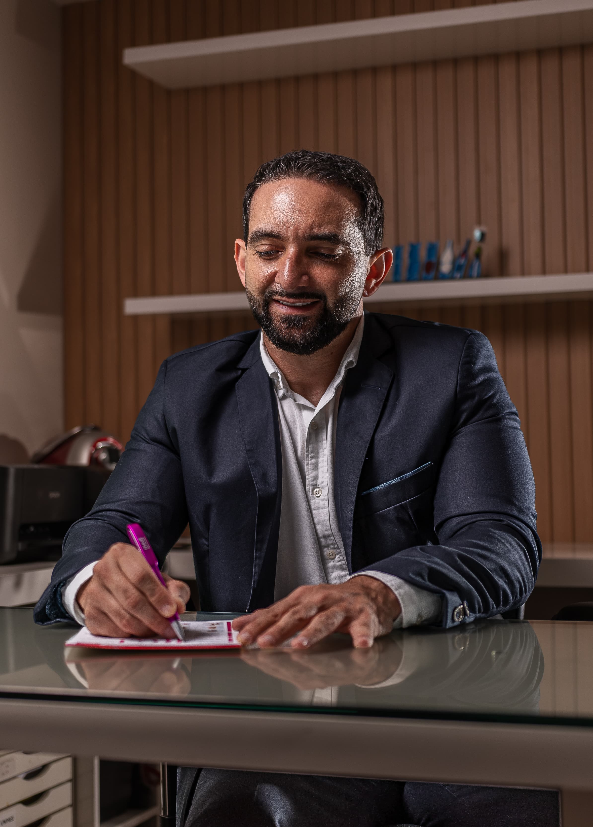 Dr. Caio, cirurgião vascular, sentado à mesa do consultório fazendo anotações.